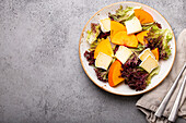 Persimmon salad with brie cheese and fresh salad leaves