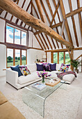 Corner sofa and glass coffee table in a converted barn with exposed wooden beams