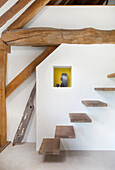 Floating staircase in a room with exposed wooden beams in a converted barn