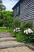 Gartenweg mit Kies und Holzbalken, gesäumt vom Blumenbeet