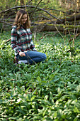 Young woman harvesting wild garlic in the forest