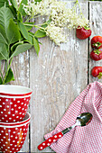 Colorful dishes, strawberries and elderflowers on a wooden surface