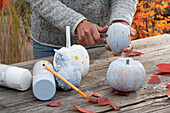 Decorate pumpkins sprayed white with craft paint after they have dried by scraping off the paint with a knife.