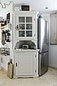 Corner cupboard with glass door panels next to fridge in vintage-style kitchen