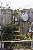 Ladder and metal tub hung on screen fence in wintery garden