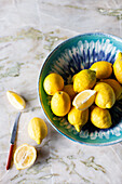 Fresh lemons in a bowl and on a marble background