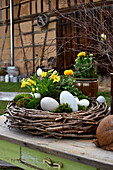Wreath of twigs with daffodils, ranunculus, moss and Easter eggs as Easter decoration