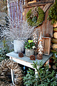 Weihnachtliches Arrangement mit Christrose, Holzbäumchen, Mooskranz, Strauß aus weißen Zweigen, Zapfen, Kranzrohling und Fichte
