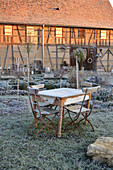 Rustic table and chairs next to cottage garden in winter