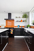 Fitted kitchen cabinets with black cupboard fronts and orange backsplash
