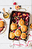 Plum cobbler with raspberries, blueberries and pistachios