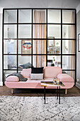 Pink designer sofa and coffee table in front of floor-to-ceiling glass wall