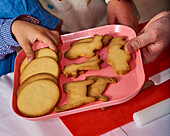 Hands holding a tray of children's biscuits
