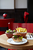 Gourmet burger with fries and salad on a bistro table