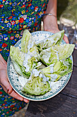 A woman serving iceberg lettuce with a yoghurt dressing