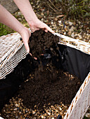 Filling a lined hamper with gravel and compost