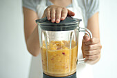Child holding blender containing peach puree