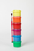 Stack of colourful pots of paint with paintbrush
