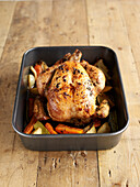 Cooked roast chicken in roasting pan with vegetables