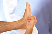 Man massaging foot with outer edge of fist