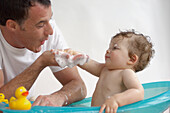 Mature adult father giving baby son bath
