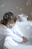 Young girl in pyjamas washing hands and making bubbles