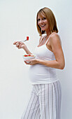 Pregnant woman holding bowl of fruit salad