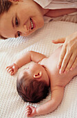 Mother bonding with baby lying on back on bed