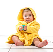 Baby girl sitting wearing yellow dressing gown