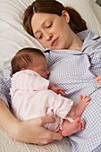 Woman lying in bed with her arm around a baby girl