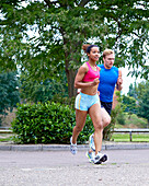 Man and woman running through a park