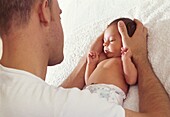 Man's hands cupped around a baby's head