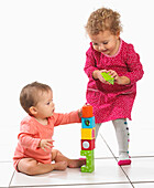 Baby girl and toddler building tower with colourful blocks