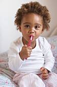 Toddler holding red toothbrush to mouth