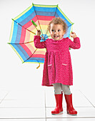 Small girl wearing wellington boots and holding umbrella