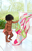 Toddler pushing patchwork quilt on top of bed