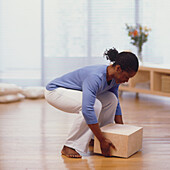 Woman leaning over to lift box off floor