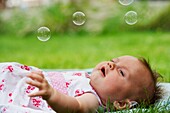 Baby girl looking at soap bubbles