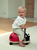 Baby boy sitting on ladybird-shaped baby walker