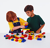Boy and girl playing with plastic toy bricks