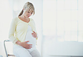 Woman in late stage of pregnancy stroking her belly