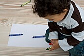 Boy crouching with crayons in his hand