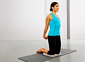 Woman kneeling on exercise mat