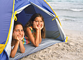 Girls lying in tent on beach