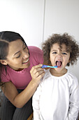 Woman brushing girl's teeth