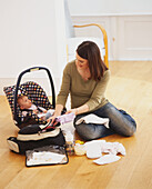 Woman packing baby clothes into a travel bag