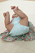 Baby girl lying on back holding feet