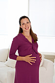 Smiling pregnant woman with hands on belly
