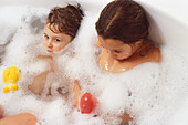 Two children in a bath of foamy water