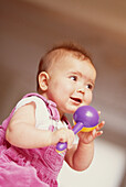 Baby holding a plastic purple rattle